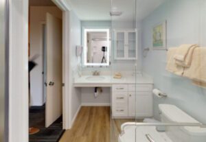 A bathroom with wood floors and white cabinets.