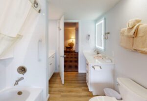 A bathroom with wood floors and white walls.