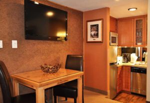 A table and chairs in a room with a television on the wall.