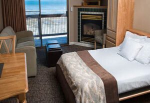 A bedroom with a fireplace and ocean view.