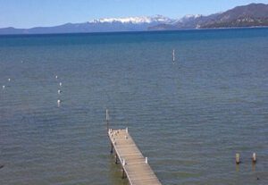 A dock in the middle of an ocean with mountains in the background.