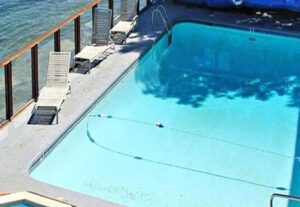 A swimming pool with a deck and stairs to the water.