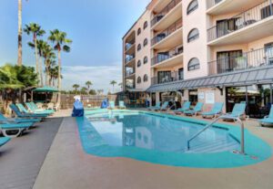 A pool with chairs and umbrellas in the background.