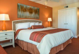 A bedroom with orange walls and white bedding.