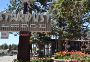 A sign for the carousel lodge in front of some flowers.