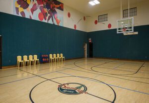 A gym with basketball court and chairs in the middle.