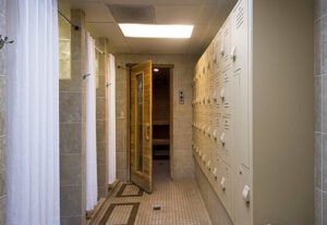 A hallway with many white lockers and a door.