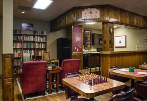 A room with a table and chairs, chess set on the floor.