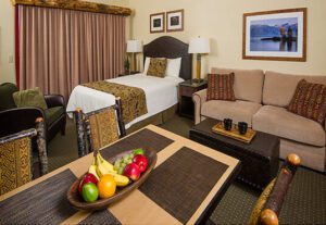 A hotel room with fruit on the bed and a couch.