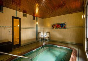 A large indoor pool with chairs around it.