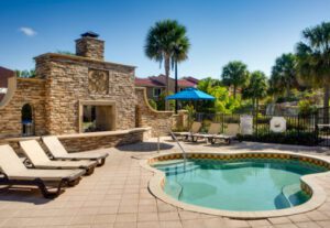 A pool with an outdoor fireplace and sun loungers.