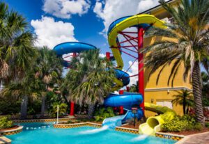 A pool with water slides and palm trees.