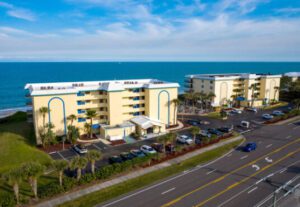 A view of the ocean from above shows cars parked on the side of the road.