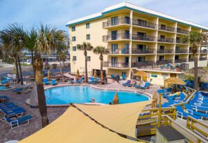 A pool and some palm trees in front of a building.