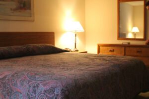 Hotel room with patterned bedspread and lamp.