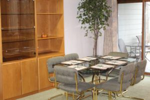 Glass dining table with six chairs near a cabinet.