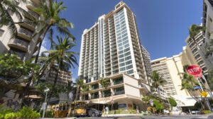 Tall building in Honolulu with palm trees.