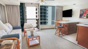 Living room with couch, balcony, and kitchen.