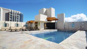 Rooftop pool with lounge chairs and building.