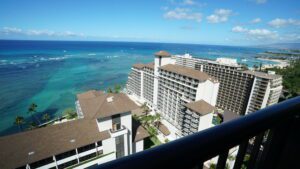 Ocean view from balcony with hotel buildings.