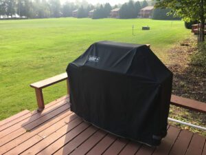 Black grill cover on a wooden deck.