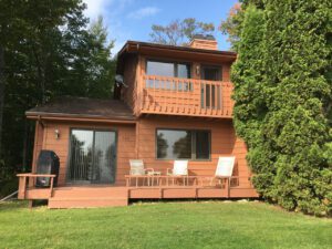 Brown wooden cabin with deck and chairs.