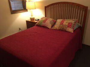 Red bed with floral patterned pillows.