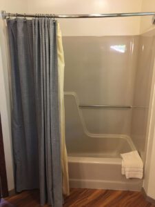 A shower stall with a grey shower curtain.