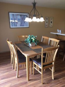 Wooden dining table with chairs and chandelier.