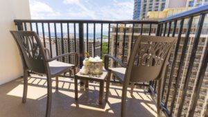 Ocean view balcony with chairs and wine.