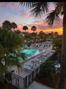 Sunset view of a resort pool and lounge chairs.