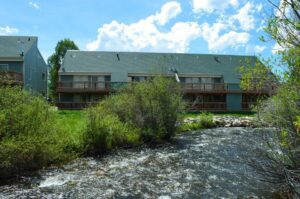 Green cabin by a rushing river.