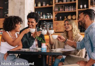 Friends laughing and toasting with drinks.